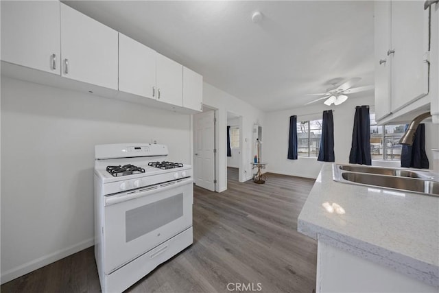 kitchen featuring white cabinets, wood finished floors, gas range gas stove, light countertops, and a sink