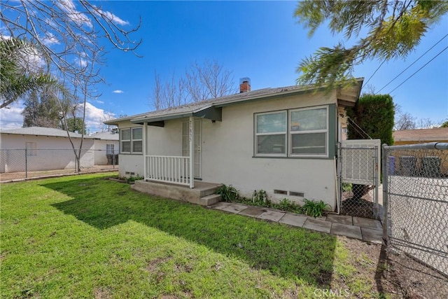 rear view of property with stucco siding, a lawn, crawl space, a gate, and fence