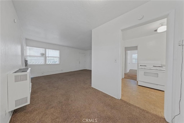 unfurnished living room featuring tile patterned flooring, carpet flooring, and heating unit