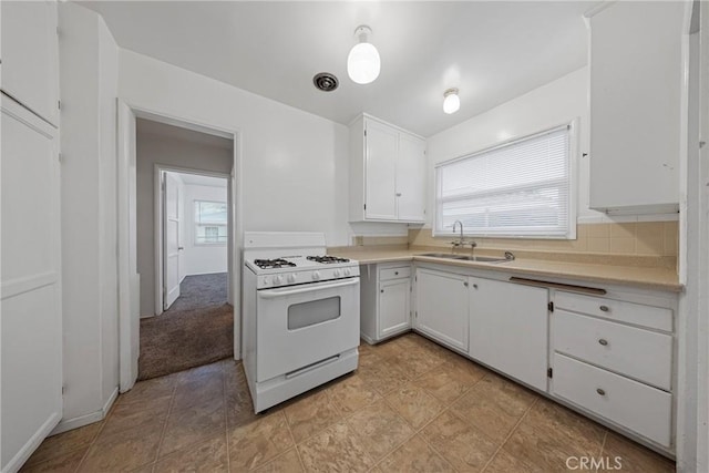 kitchen featuring light countertops, white cabinets, a sink, and white gas range oven