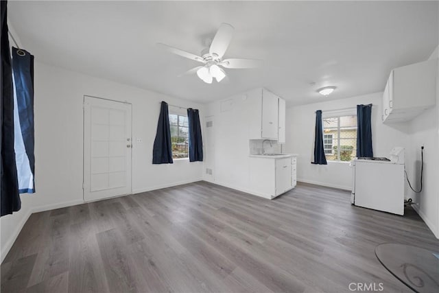 interior space with wood finished floors, a sink, a ceiling fan, and baseboards