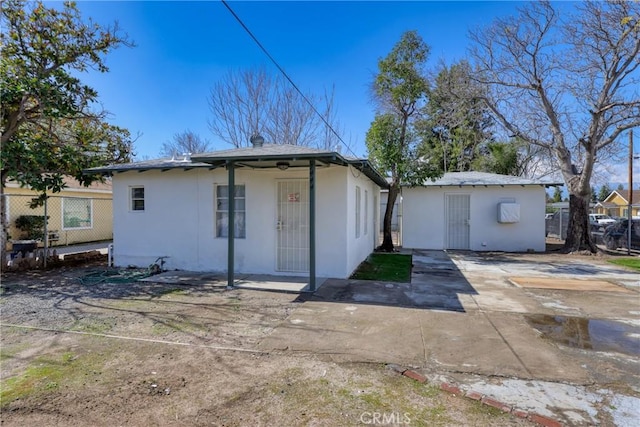 back of property featuring an outbuilding, fence, and stucco siding