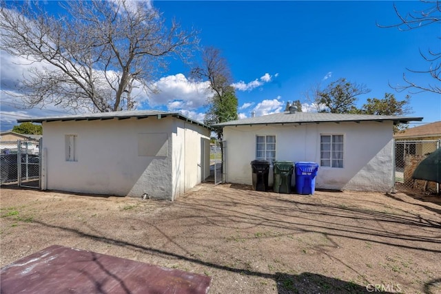 back of property with an outbuilding, fence, and stucco siding