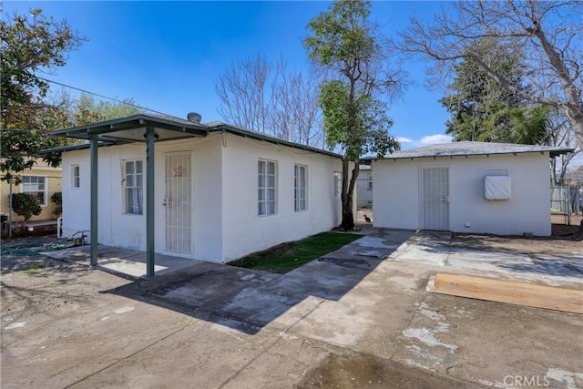 view of front facade featuring an outbuilding, a patio area, and stucco siding