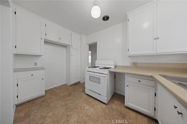 kitchen with light countertops, white cabinets, white gas stove, and visible vents