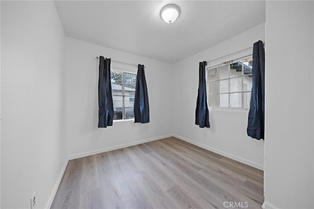 spare room with baseboards and wood finished floors