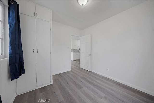 unfurnished bedroom featuring a closet, wood finished floors, and baseboards