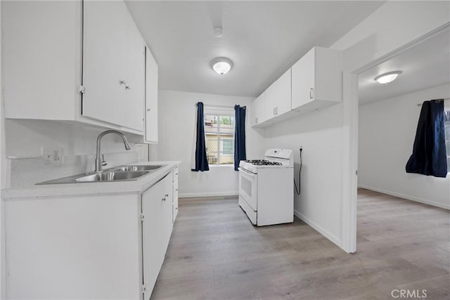 laundry area featuring light wood finished floors, a sink, and baseboards