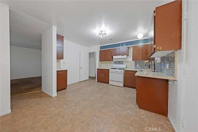 kitchen with a sink, light countertops, under cabinet range hood, white stove, and backsplash