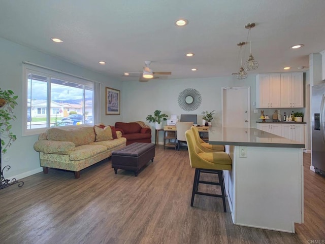 kitchen featuring stainless steel fridge with ice dispenser, dark wood-style floors, open floor plan, a breakfast bar, and white cabinetry