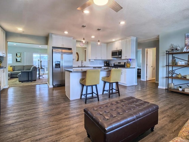 kitchen featuring open floor plan, stainless steel appliances, a kitchen island, and white cabinets