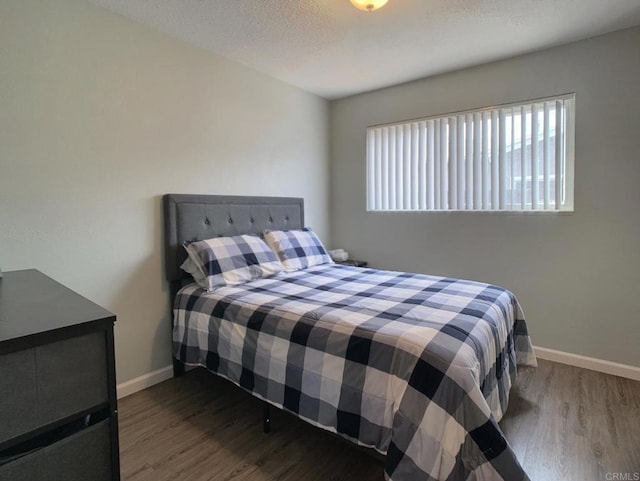 bedroom featuring a textured ceiling, wood finished floors, and baseboards