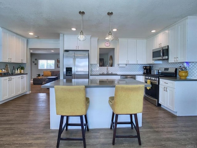 kitchen featuring stainless steel appliances, dark wood-style flooring, a sink, and a kitchen breakfast bar