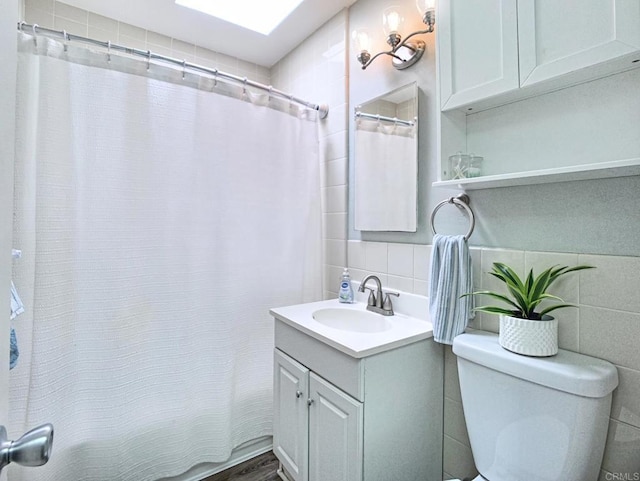 full bath with toilet, tile walls, and vanity