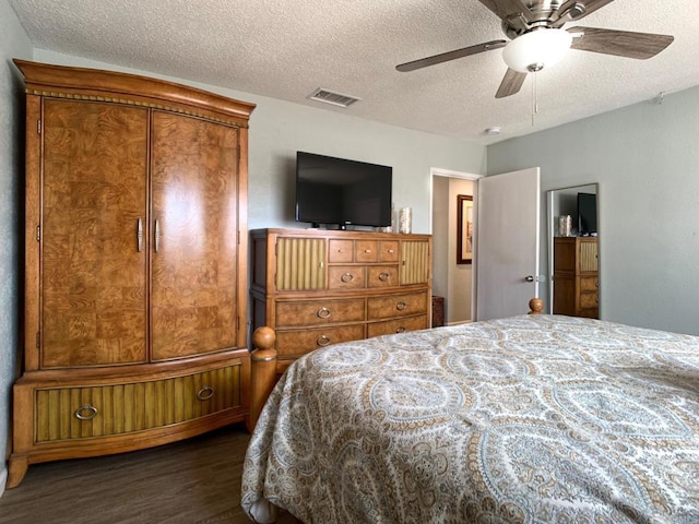 bedroom featuring dark wood-style floors, a ceiling fan, visible vents, and a textured ceiling