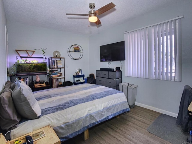 bedroom featuring ceiling fan, a textured ceiling, baseboards, and wood finished floors