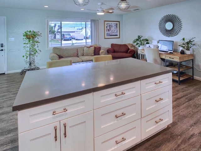 kitchen with dark wood-style floors, dark countertops, open floor plan, and white cabinetry