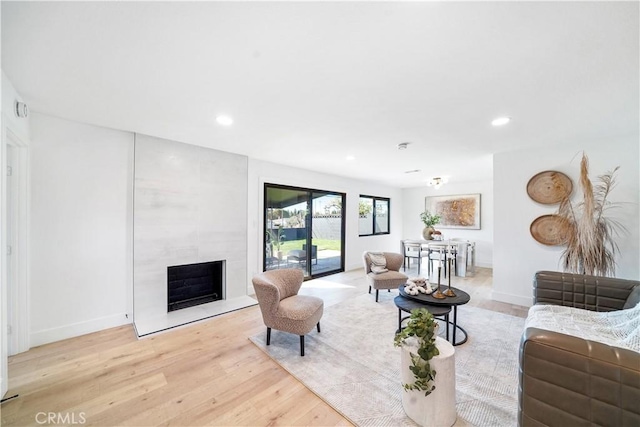 living area with recessed lighting, baseboards, light wood-style floors, and a fireplace