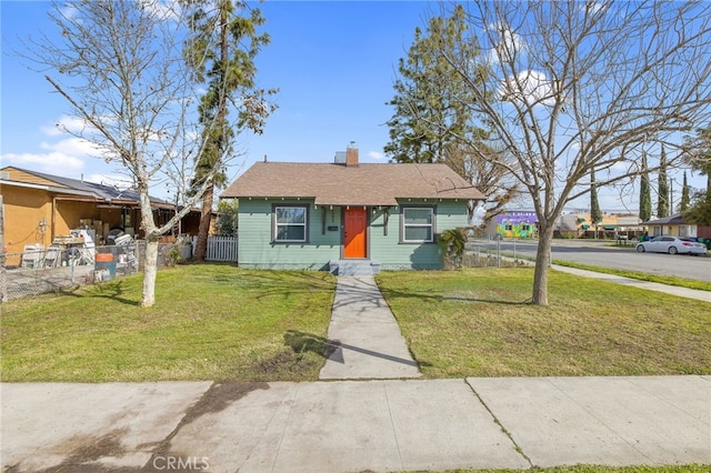 bungalow featuring a chimney, fence, and a front yard