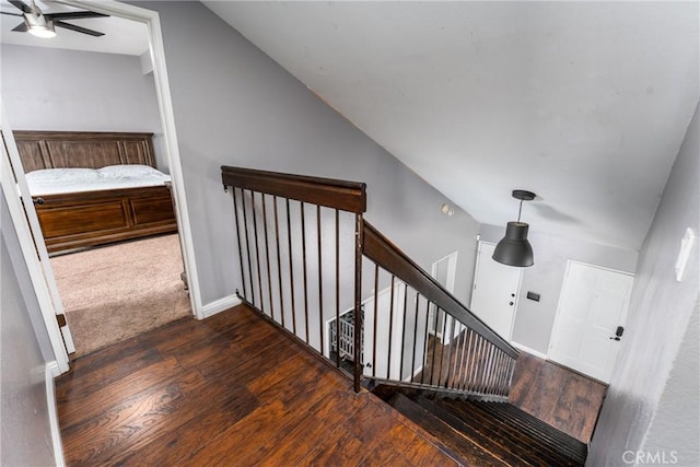 stairway featuring lofted ceiling, ceiling fan, baseboards, and hardwood / wood-style floors