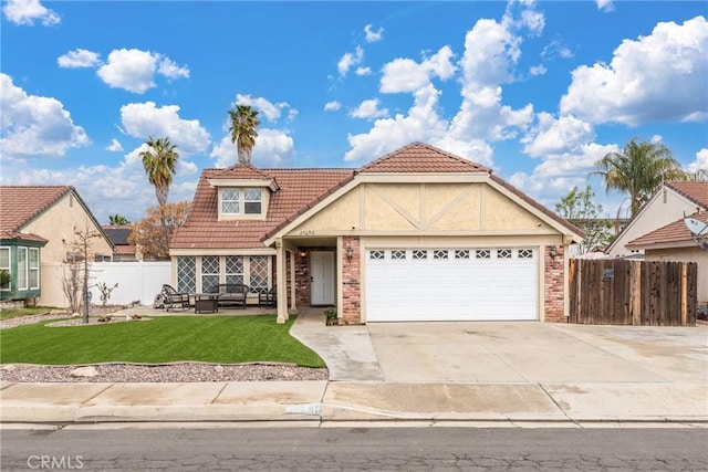 view of front facade with a tile roof, a front yard, fence, a garage, and driveway