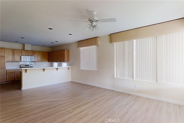 kitchen featuring light wood-type flooring, light countertops, a peninsula, and a breakfast bar area