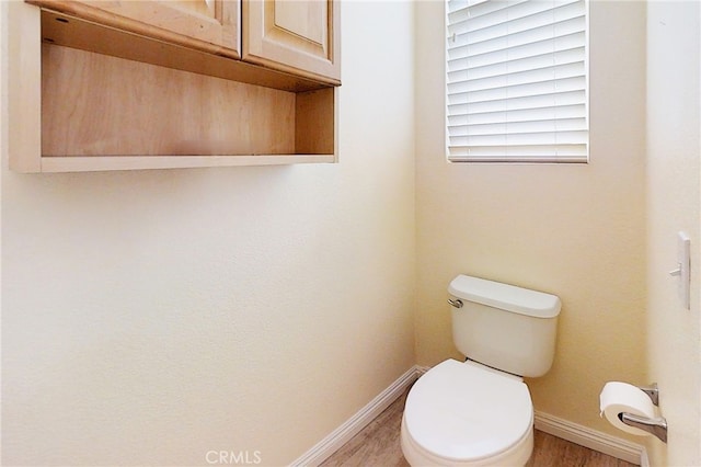 bathroom featuring baseboards, toilet, and wood finished floors