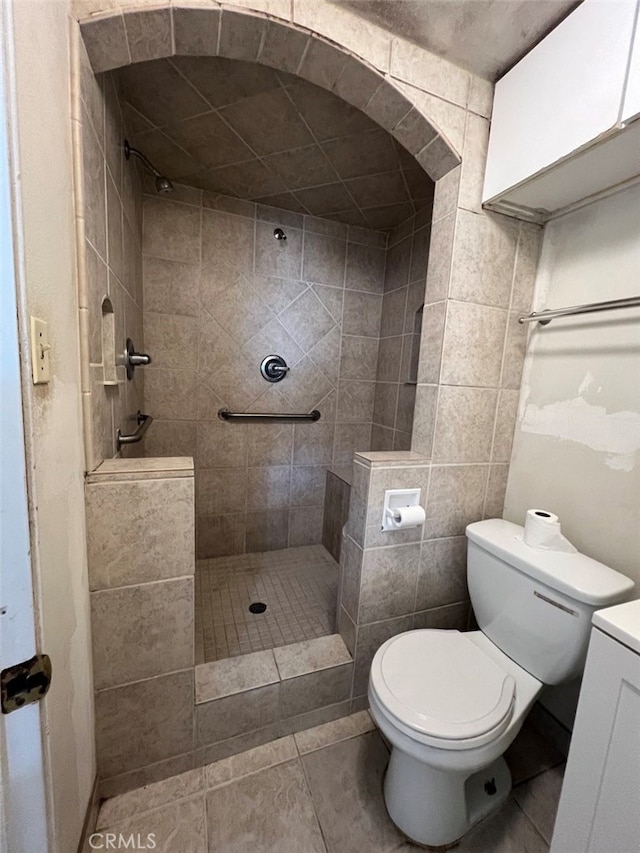 full bathroom with tiled shower, toilet, and tile patterned floors