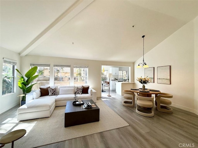 living area featuring light wood-style floors, a healthy amount of sunlight, beamed ceiling, and high vaulted ceiling