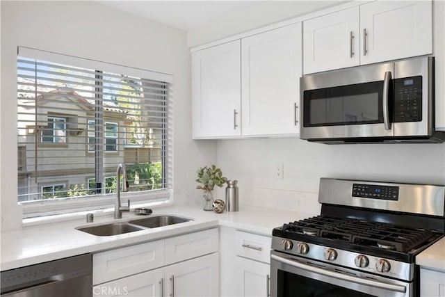 kitchen with stainless steel appliances, light countertops, a sink, and white cabinetry