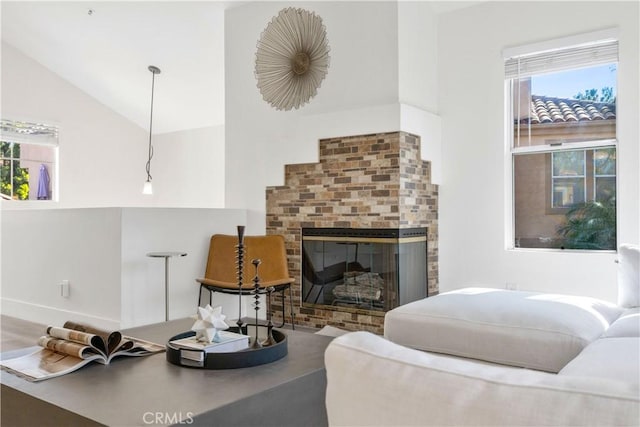 living area featuring vaulted ceiling and a brick fireplace