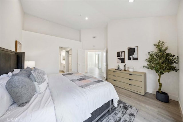 bedroom featuring ensuite bathroom, high vaulted ceiling, light wood-style flooring, recessed lighting, and baseboards