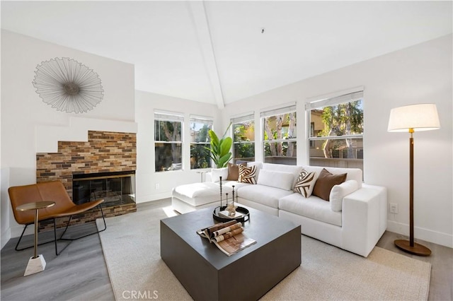 living area featuring light wood-style floors, lofted ceiling, a fireplace, and baseboards