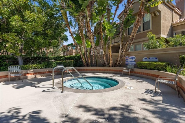 view of pool with a community hot tub, a patio area, and fence