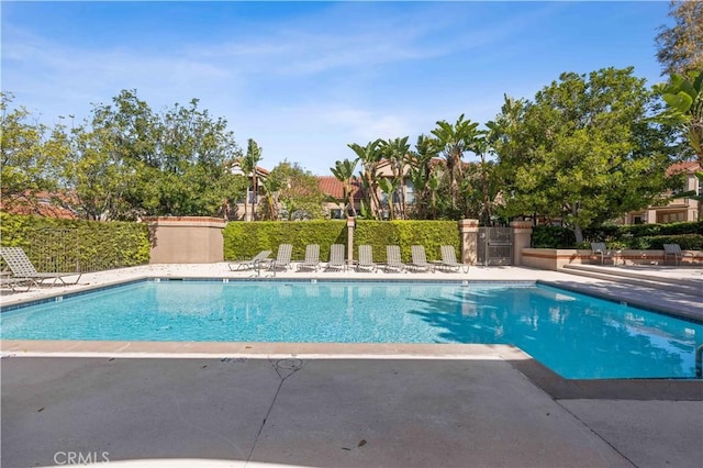 community pool with fence and a patio