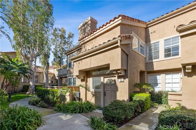 exterior space featuring a tile roof and stucco siding