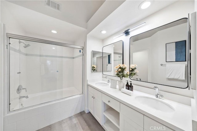 bathroom featuring tiled shower / bath, wood finished floors, a sink, and visible vents