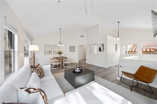 living area featuring high vaulted ceiling, visible vents, and wood finished floors