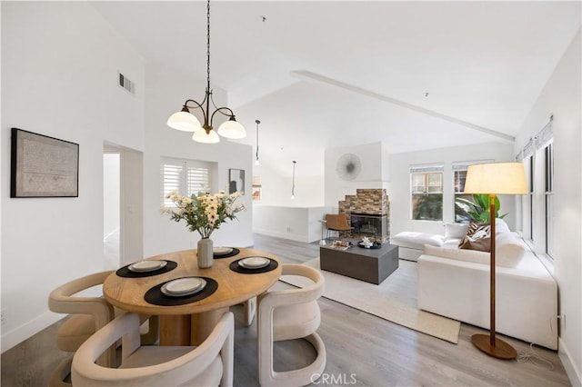 dining area with plenty of natural light, visible vents, wood finished floors, and a stone fireplace