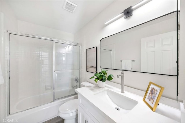 bathroom with toilet, combined bath / shower with glass door, vanity, and visible vents