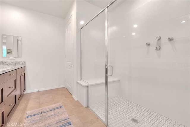 bathroom with tile patterned flooring, a stall shower, vanity, and baseboards