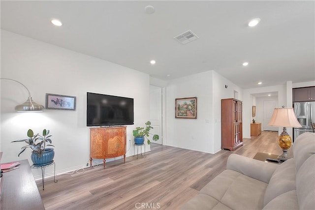 living room with recessed lighting, visible vents, baseboards, and light wood-style flooring