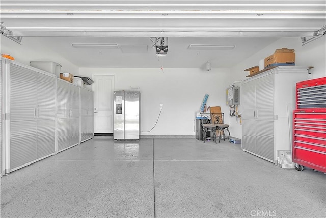 garage with a garage door opener and stainless steel refrigerator with ice dispenser