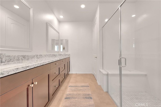 full bathroom with a stall shower, a sink, recessed lighting, double vanity, and baseboards