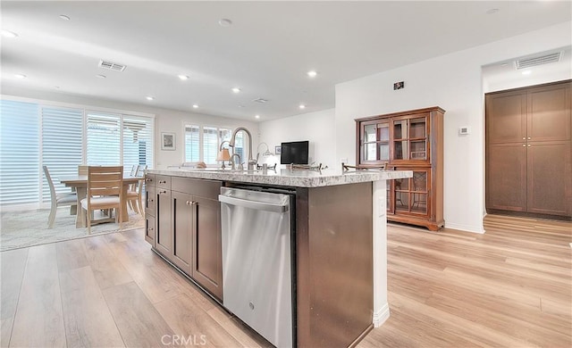 kitchen with light wood finished floors, visible vents, a sink, and stainless steel dishwasher