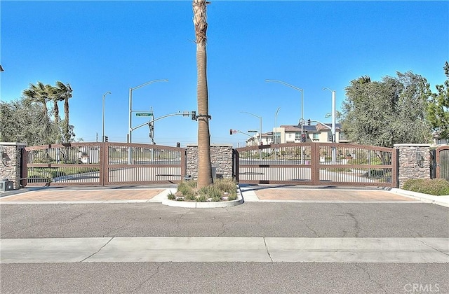 view of road with curbs, a gated entry, street lighting, and a gate