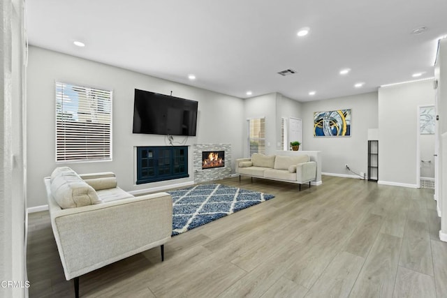 living room featuring recessed lighting, visible vents, a stone fireplace, and wood finished floors