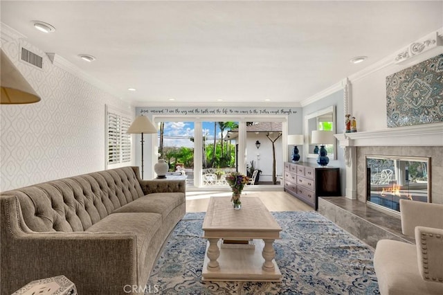 living area with ornamental molding, visible vents, a fireplace, and wallpapered walls