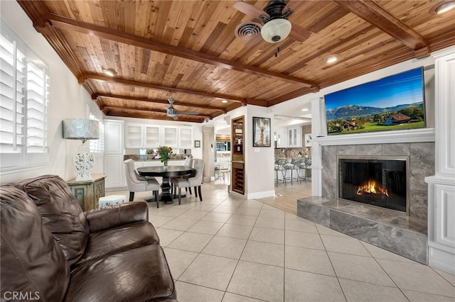 living room with light tile patterned floors, wood ceiling, a premium fireplace, and beamed ceiling