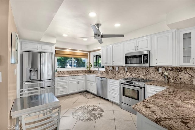 kitchen with light tile patterned floors, stainless steel appliances, backsplash, and white cabinets